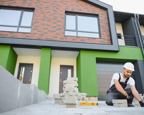 Indian worker lay paving tiles, construction of brick pavement, men's hands in gloves